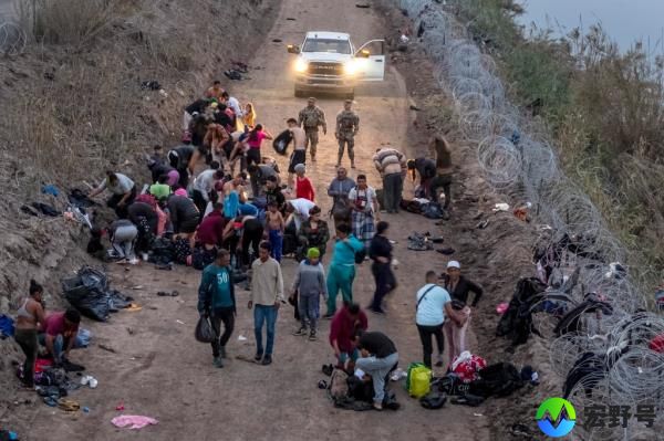Seen from an aerial view, Texas Natio<em></em>nal Guard troops look on as immigrants change into dry clothes after wading through the Rio Grande 