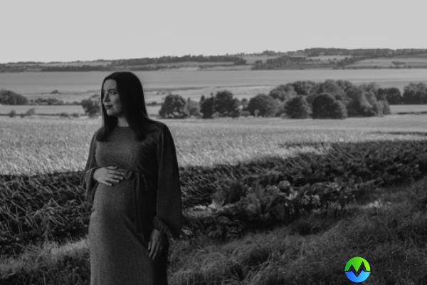 Siobhan Smith posing in a field while heavily pregnant
