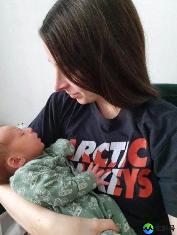 Kat Romero wearing a black Arctic Mo<em></em>nkeys t-shirt, holding her baby.